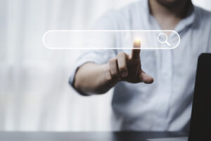 main qui touche une barre de moteur de recherche pour effectuer une requête